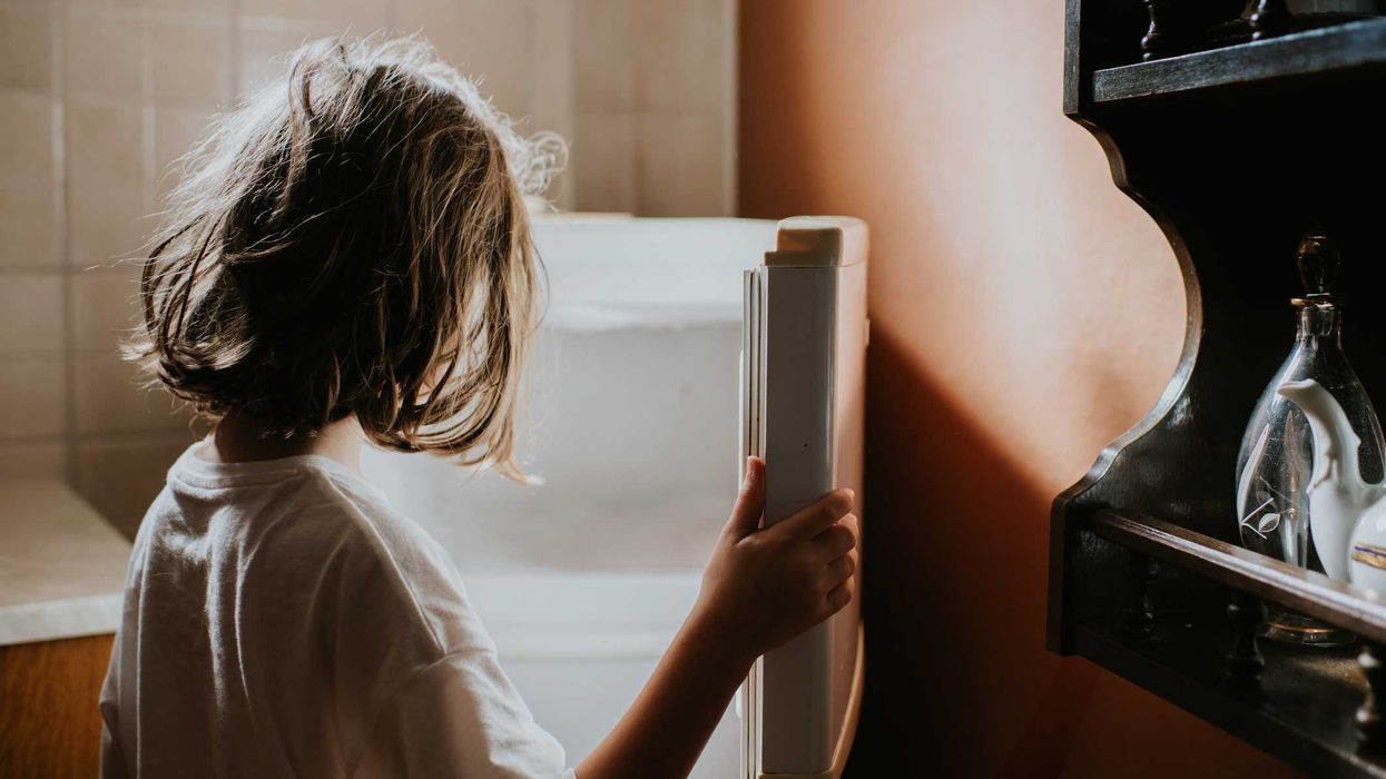 A child looks into an empty fridge-freezer in a domestic kitchen.