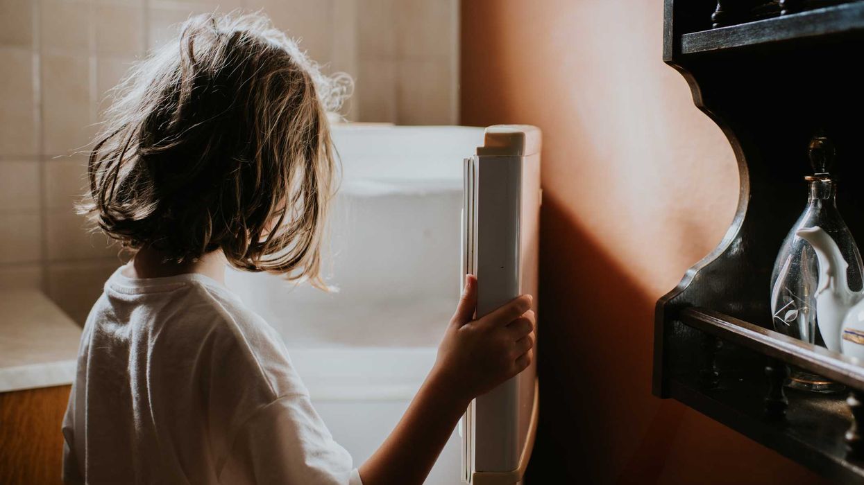 A child looks into an empty fridge-freezer in a domestic kitchen.