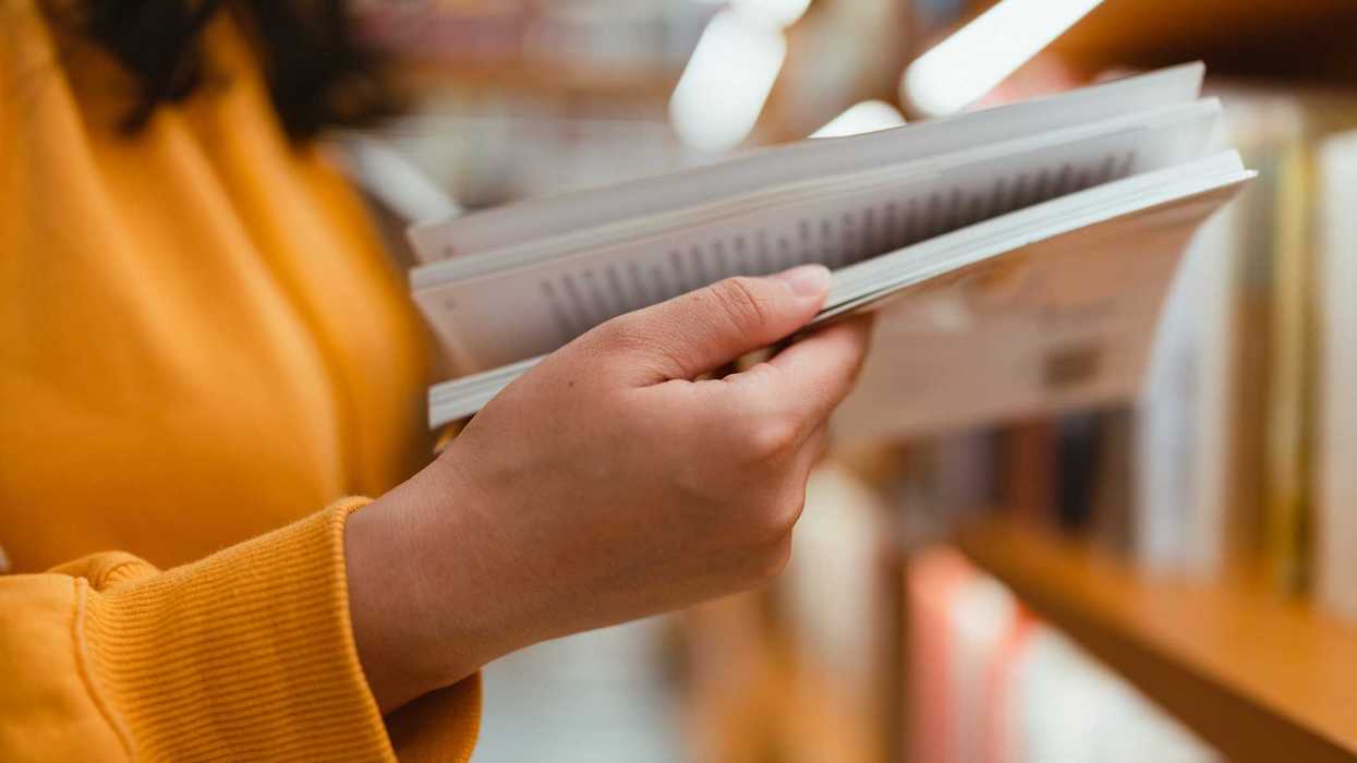 A close up of a person reading a book in a bookstore.