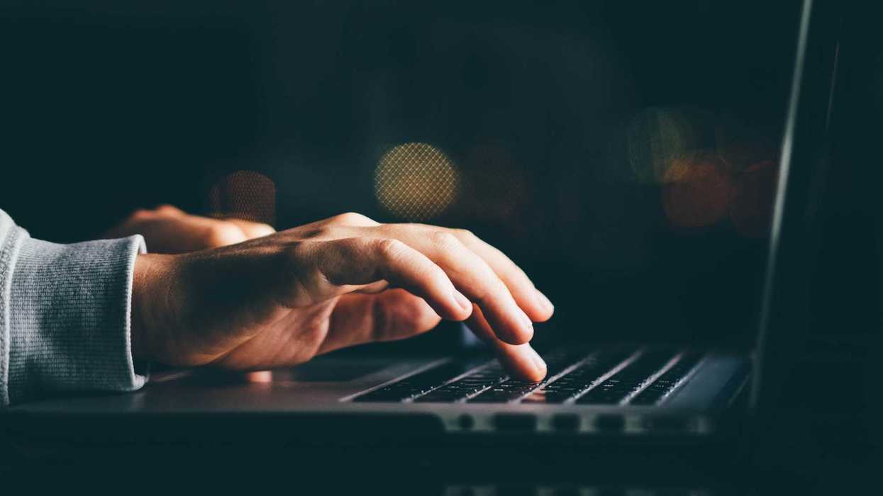 A close up of a person's hands typing on a laptop.