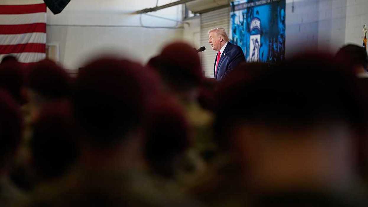 A crowd of people at a military base with President Trump speaking in front of them.