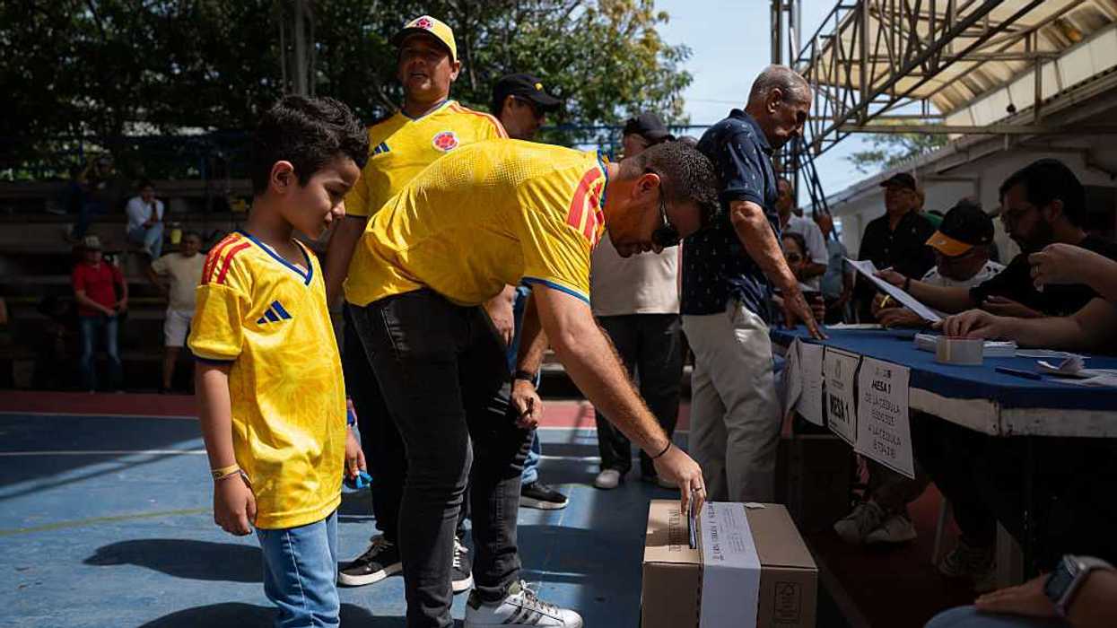 A father voting, with his young son standing by him, watching him.