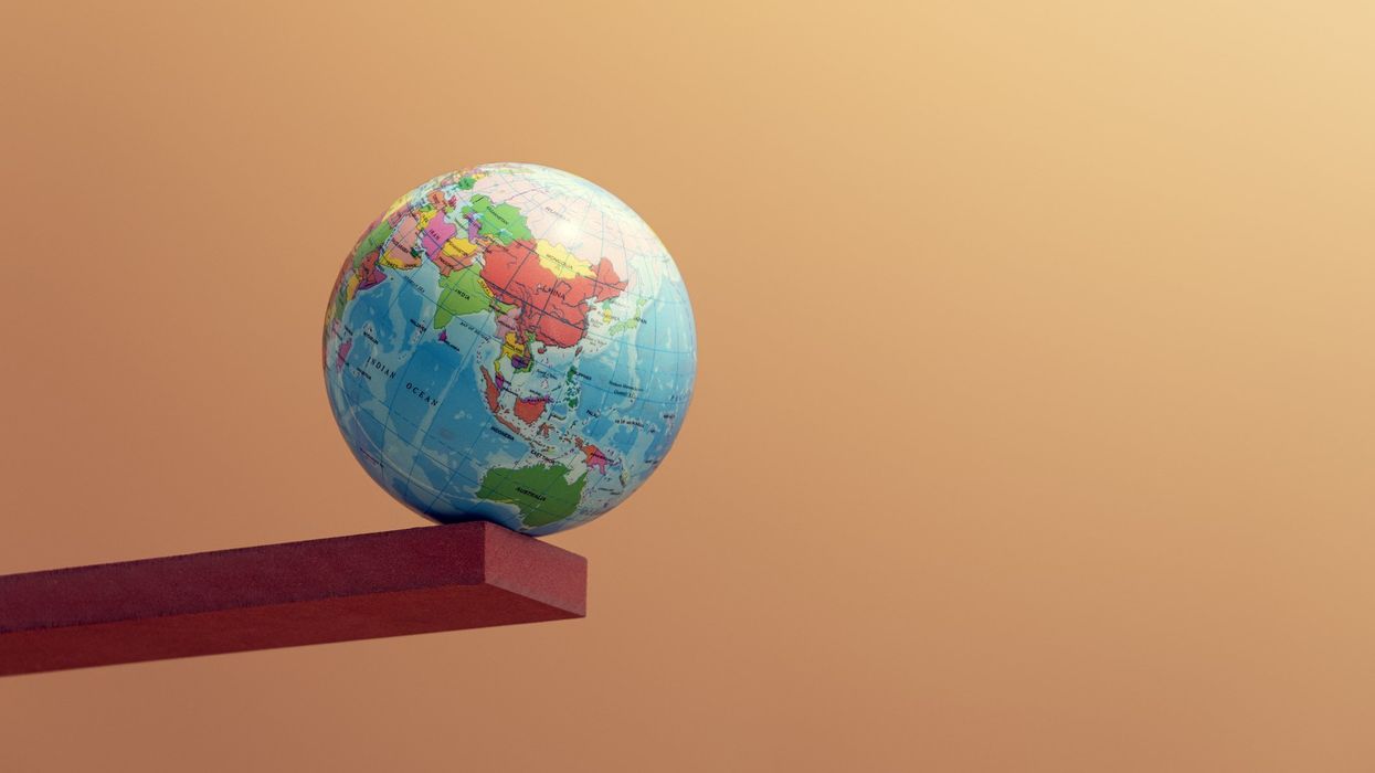 A globe resting on the very edge of a risen plank.