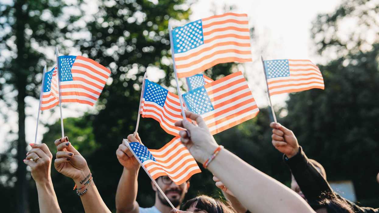 A group of people is waving small American flags at sunset. Concept for various topics like Happy Veterans Day, Labour Day, Independence Day.