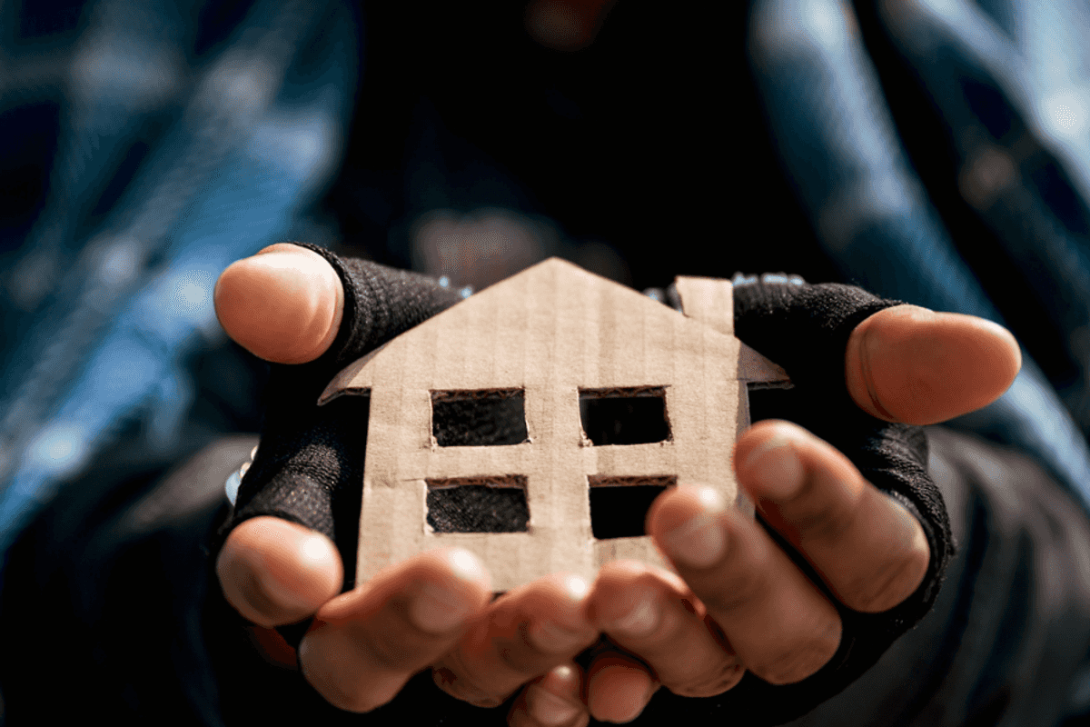 a house made of brown cardboard in a person's hands.