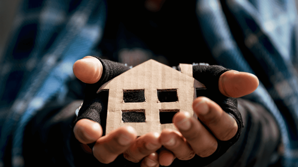 a house made of brown cardboard in a person's hands.