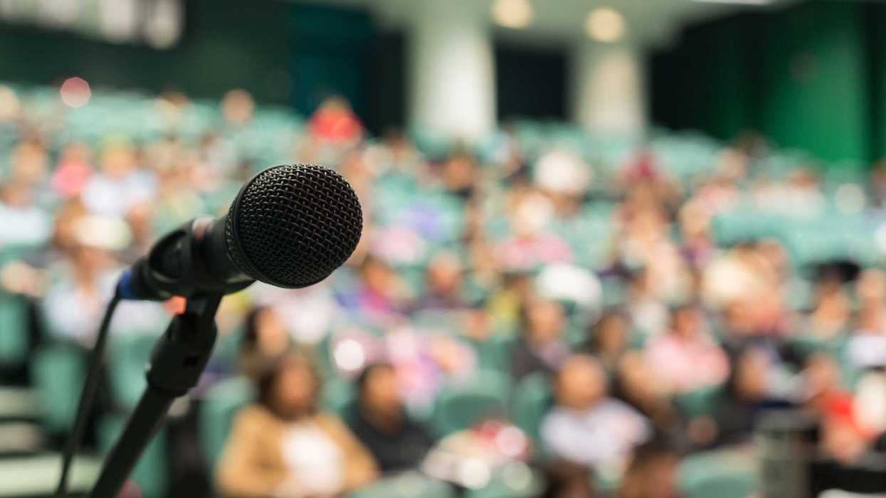 A microphone in the foreground and a crowd, blurry in the background.
