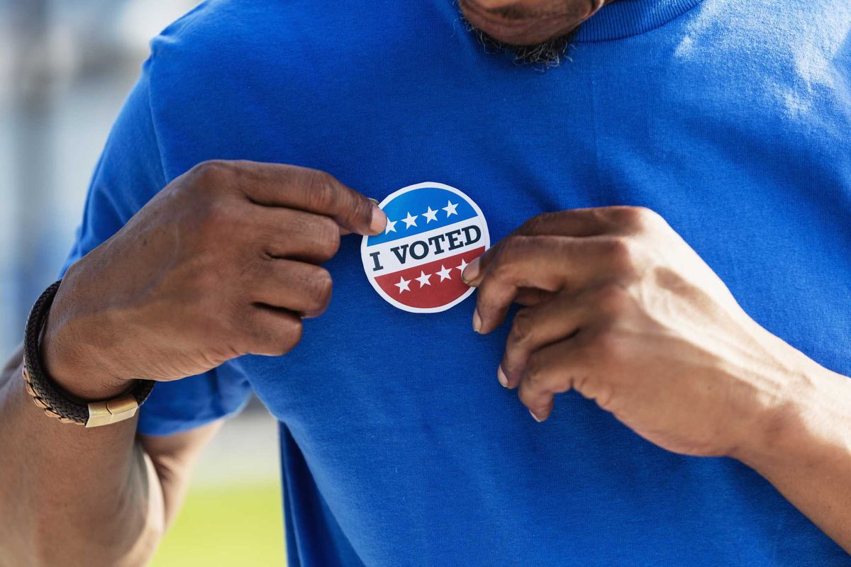 A person putting on an "I Voted" sticker.