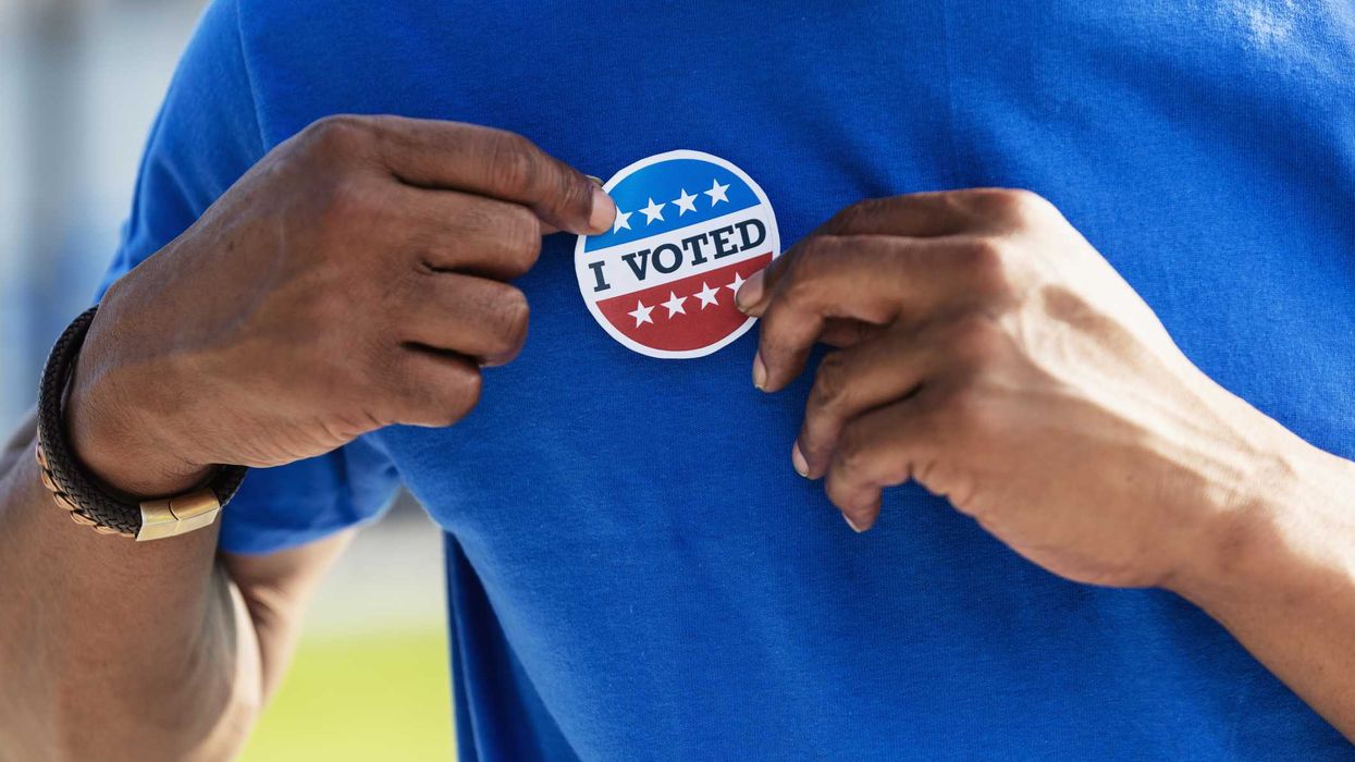 A person putting on an "I Voted" sticker.