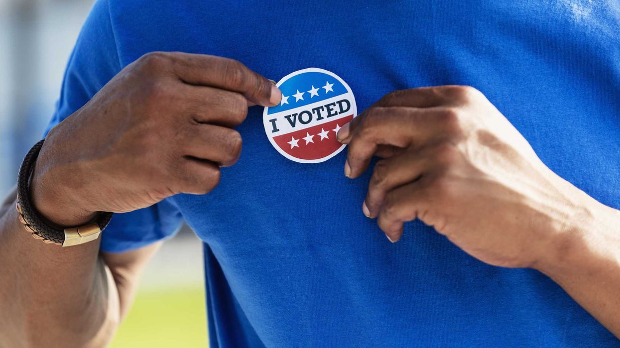 A person putting on an "I Voted" sticker.