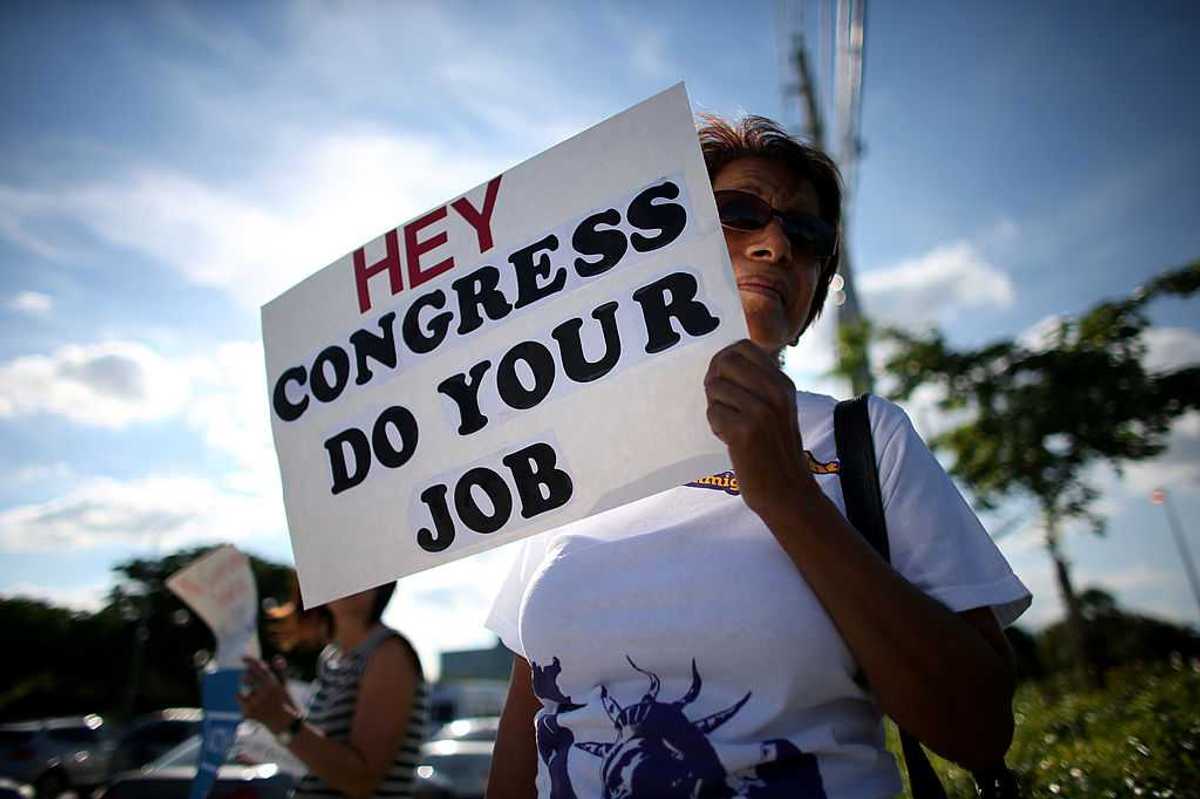 A protestor holding a sign that reads "Hey Congress Do Your Job."