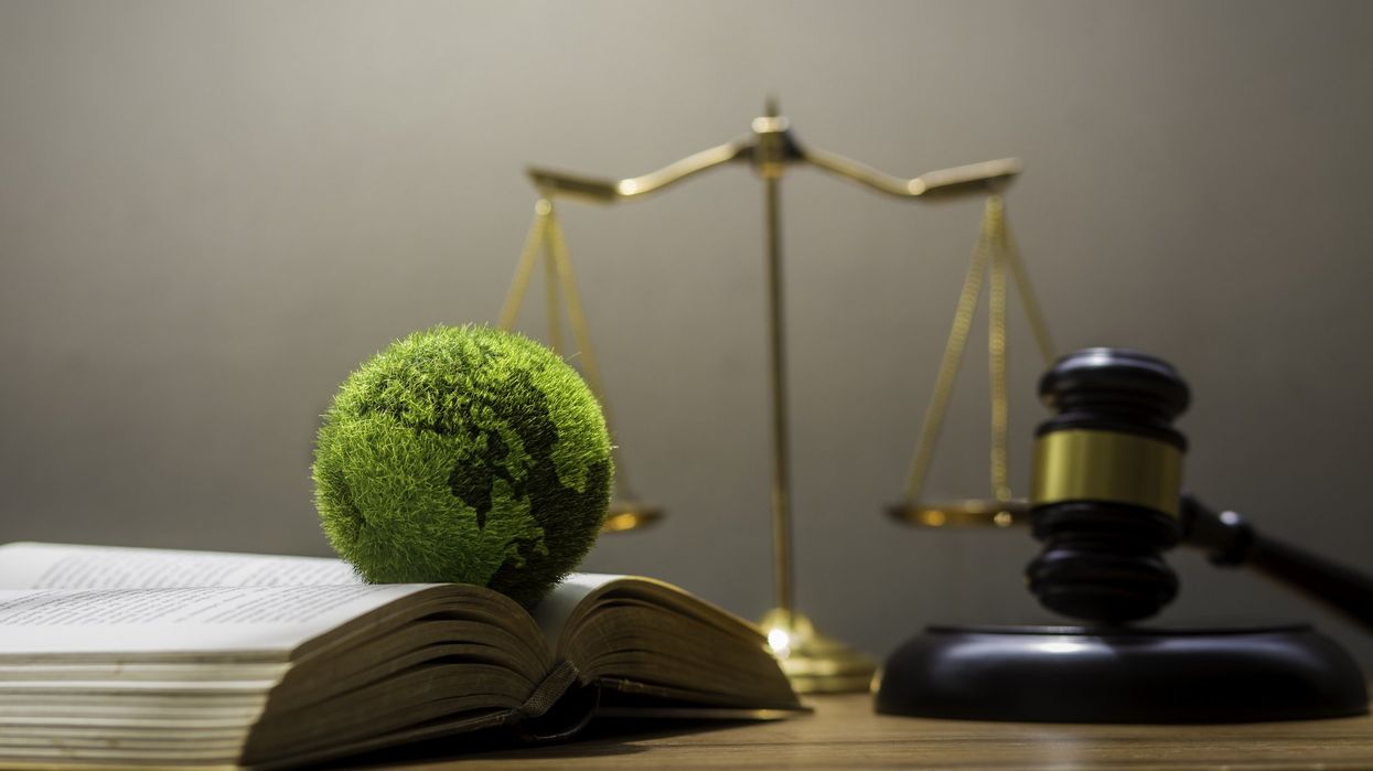 A small earth by a book, scale of justice, and gavel.