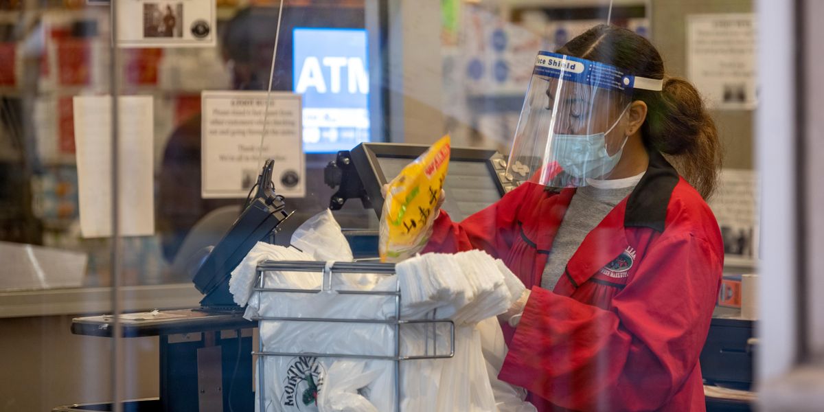A supermarket employee bags groceries in a bag during the coronavirus pandemic.