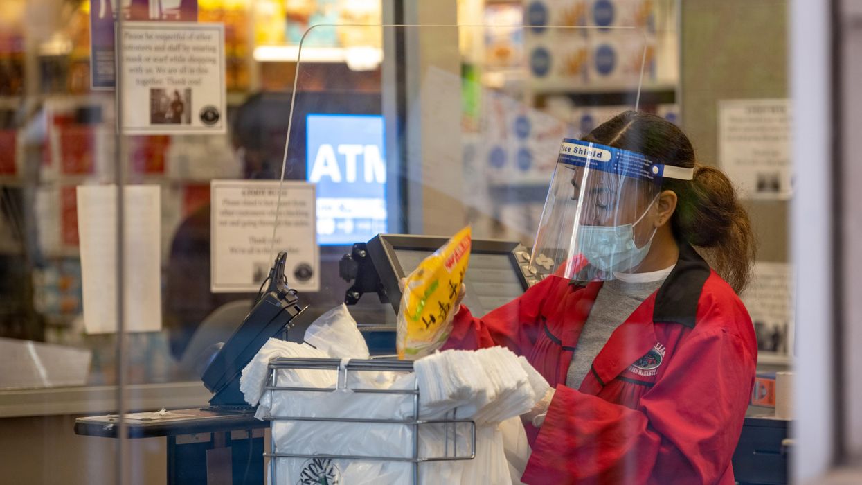 A supermarket employee bags groceries in a bag during the coronavirus pandemic.