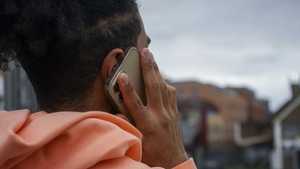 A young man holding a smartphone to his ear.