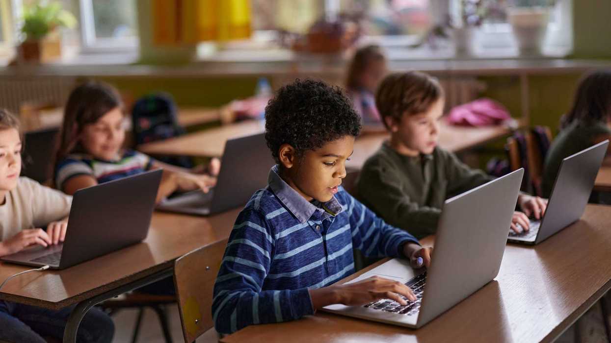 African American elementary student and his friends studying over computers during a class in the classroom.
