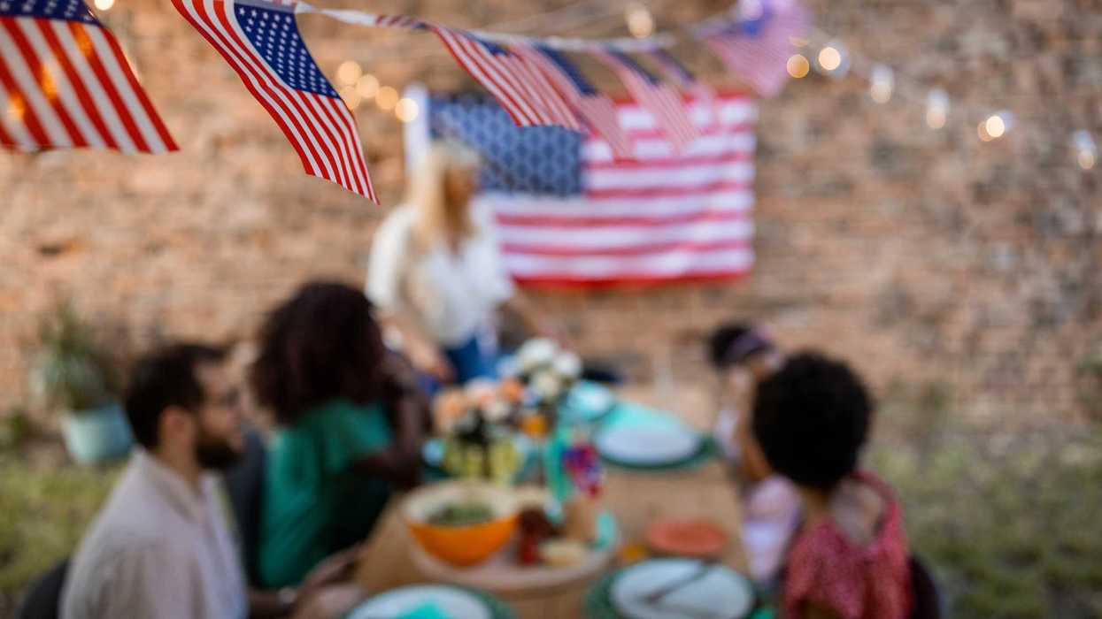 American flags flying over a family having dinner outdoors.