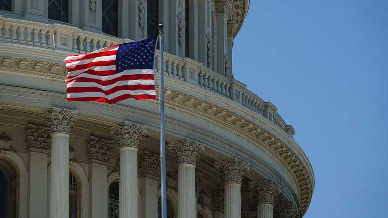 An American flag waves in front to the U.S. Capitol Building