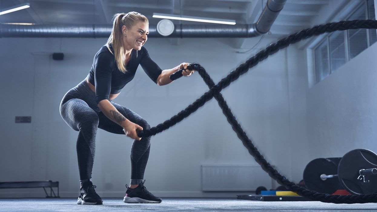 Athletic woman exercising with battle ropes at gym