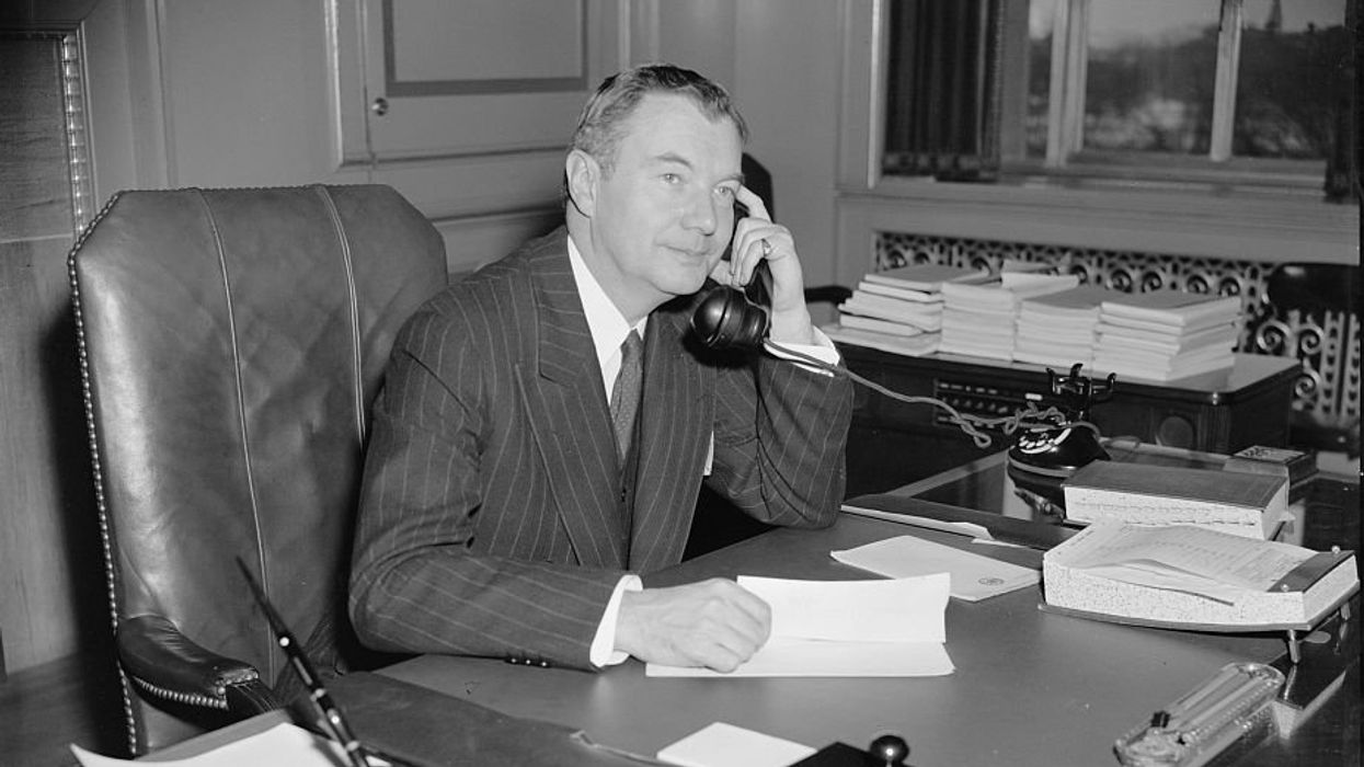 Black and white photo of a man at a desk and on the phone