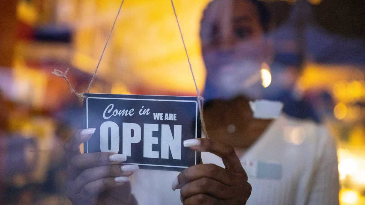 Business owner hanging an open sign at a cafe