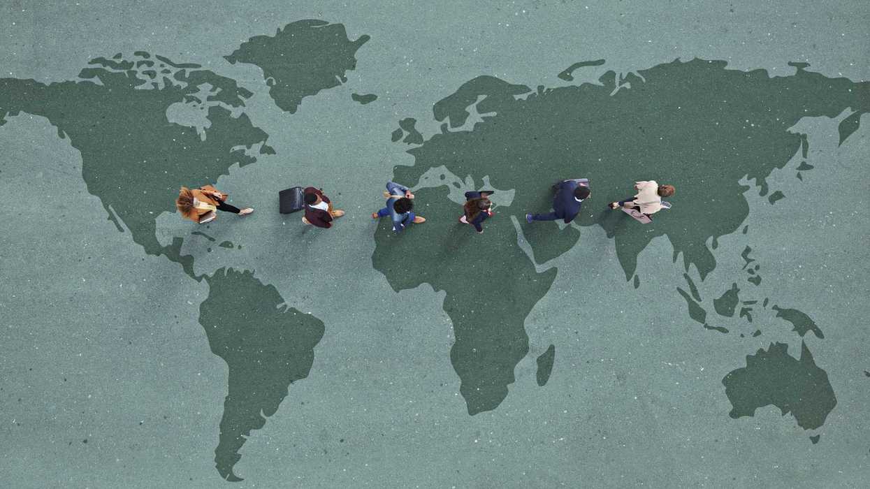 Businesspeople walking in line across world map, painted on asphalt