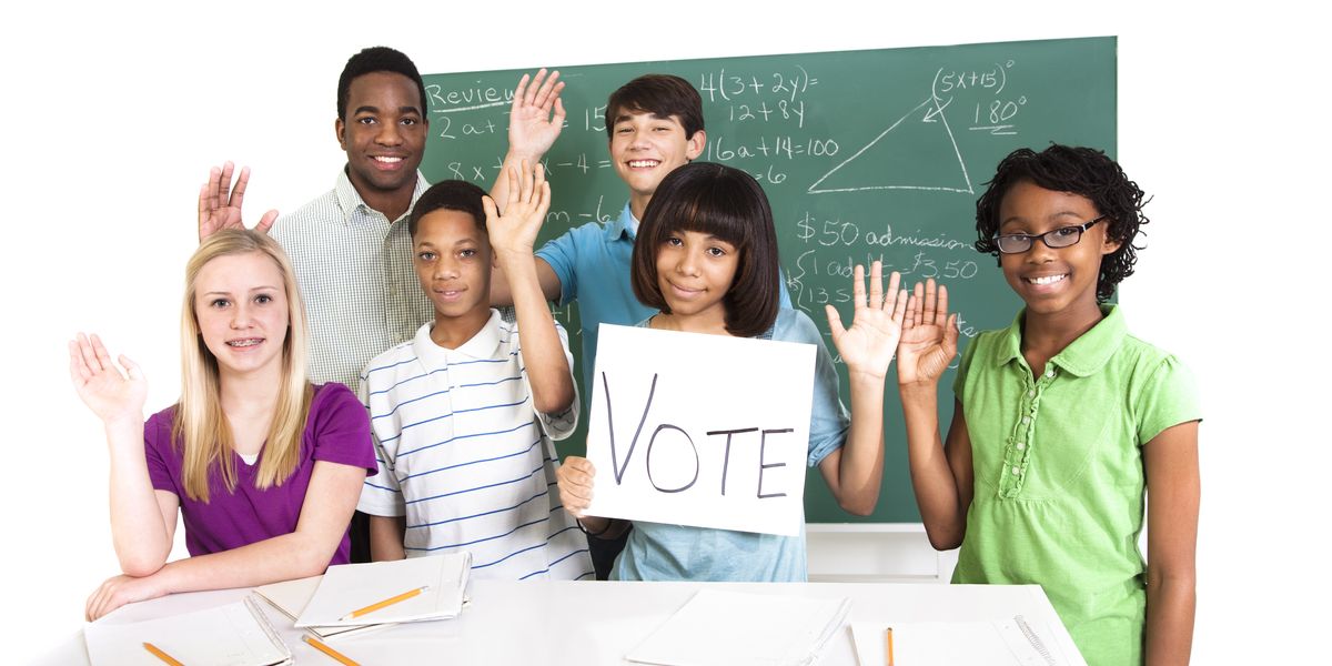 Children in school raising their hands to vote