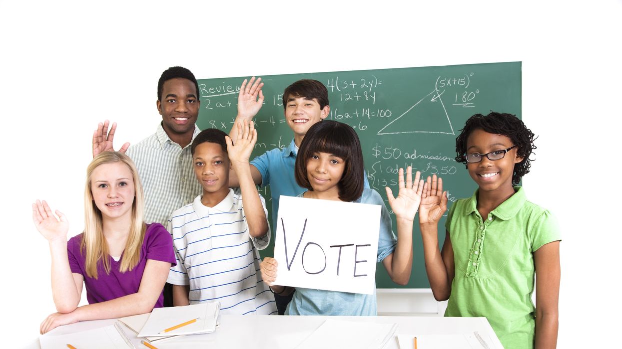 Children in school raising their hands to vote