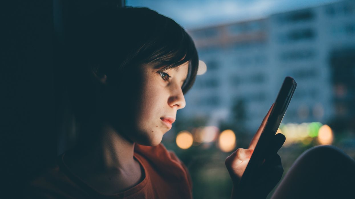 Close-up of boy looking at his phone in the dark