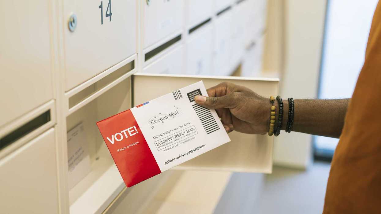Close up of hand taking voting ballot from mailbox.