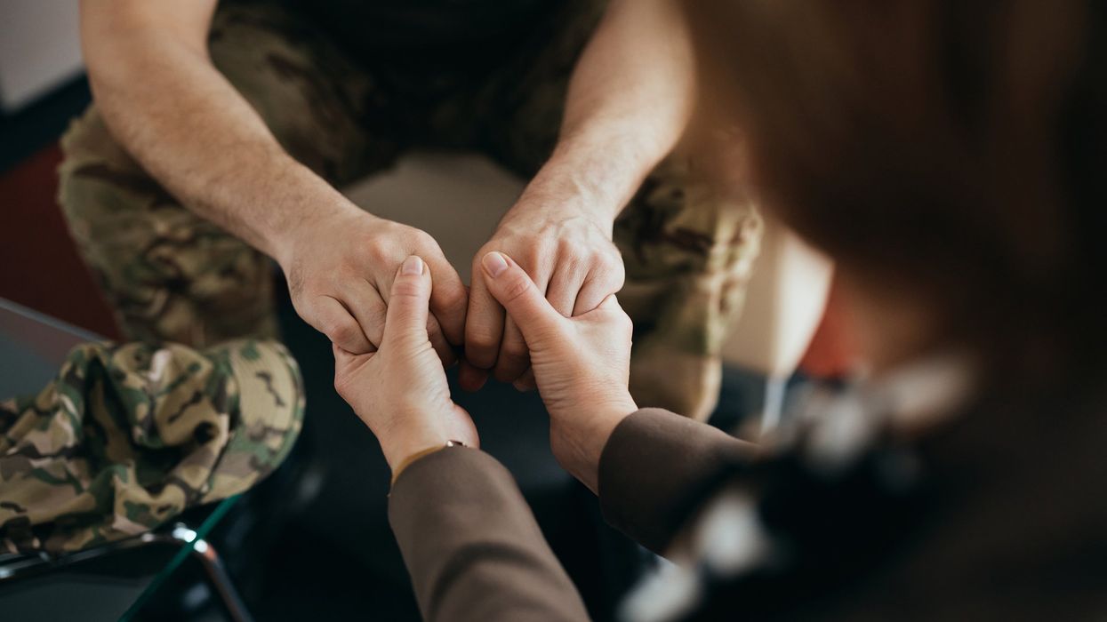 Close-up of military man holding hands with his therapist during counseling at mental health center.