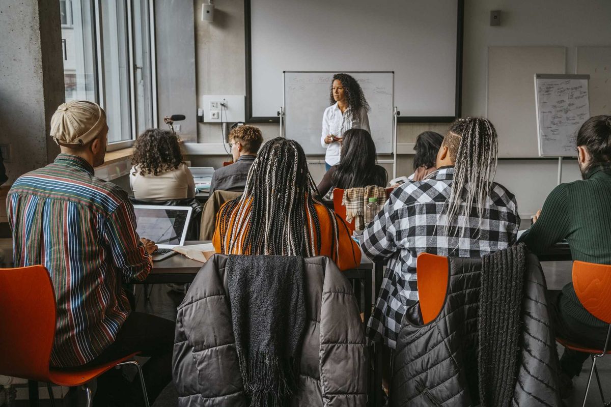 College students sitting in a classroom, facing a professor.