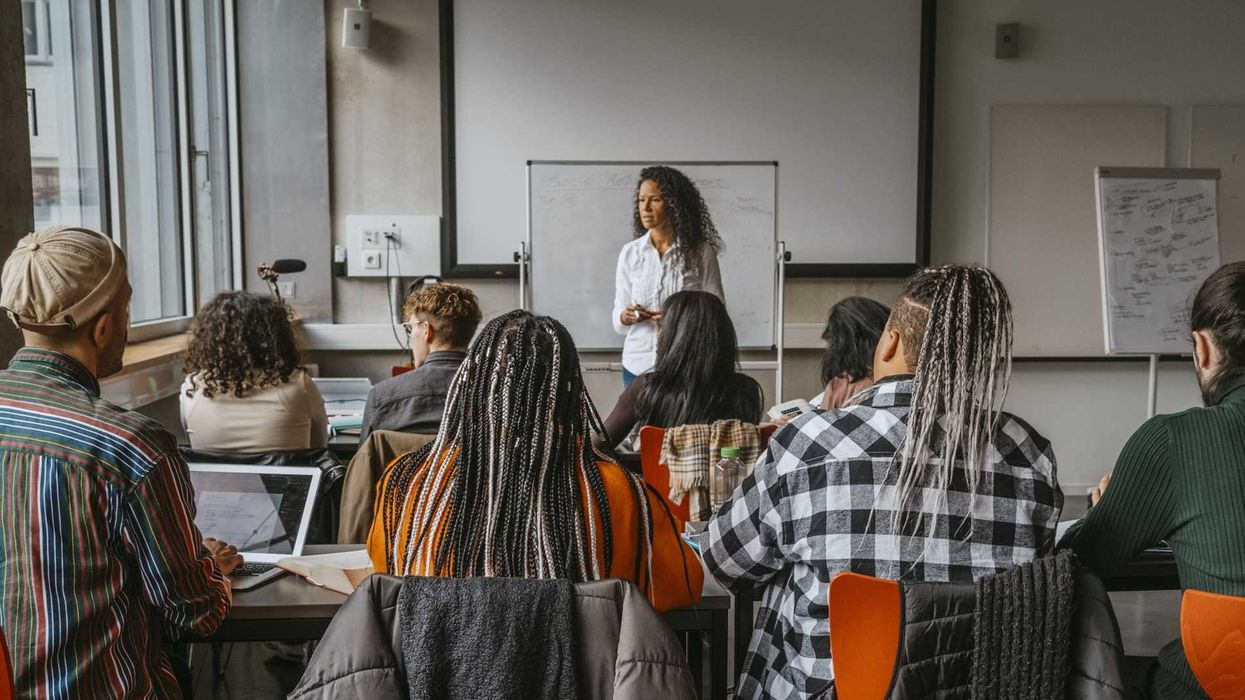 College students sitting in a classroom, facing a professor.