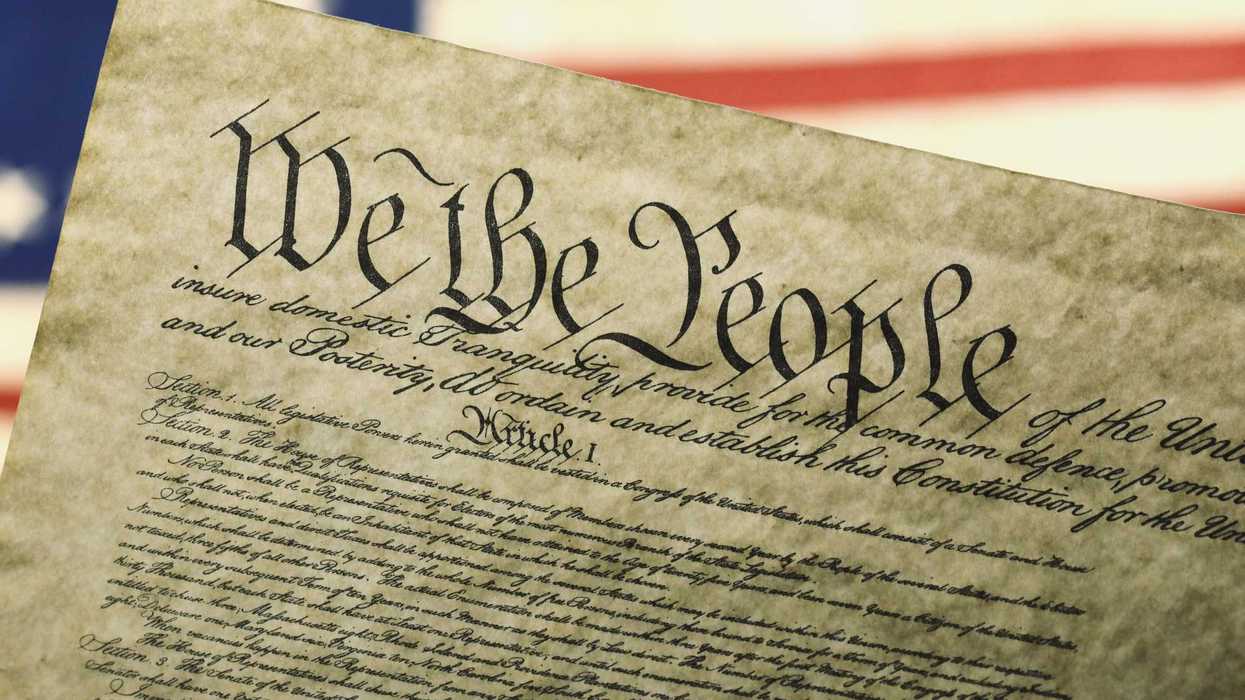 Constitution of the United State with the U.S. flag in the background.