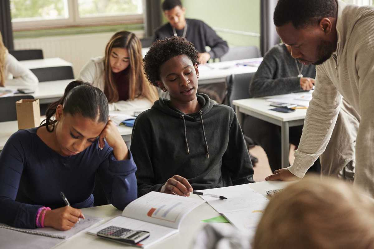 Creative Images Creative Images & Video Images Creative Editorial Video Creative Editorial Search by image or video Teenage boy getting help from male professor in solving math problem at school