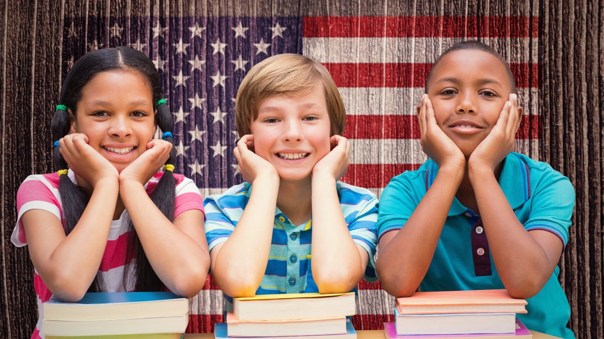 Cute pupils looking at camera in library against composite image of usa national flag