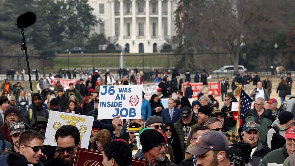 Demonstrators hold signs during a January 6th memorial march in Washington, DC.
