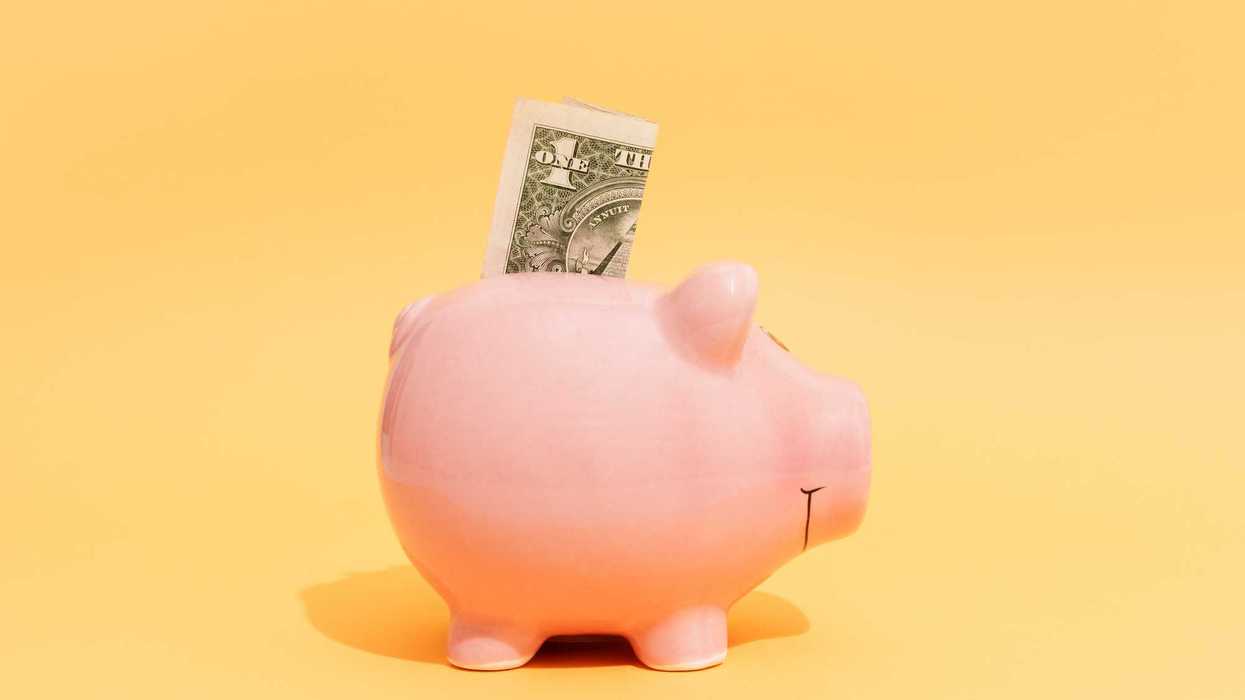 Dollar Bill Sticking Out of Piggy Bank on Yellow Background
