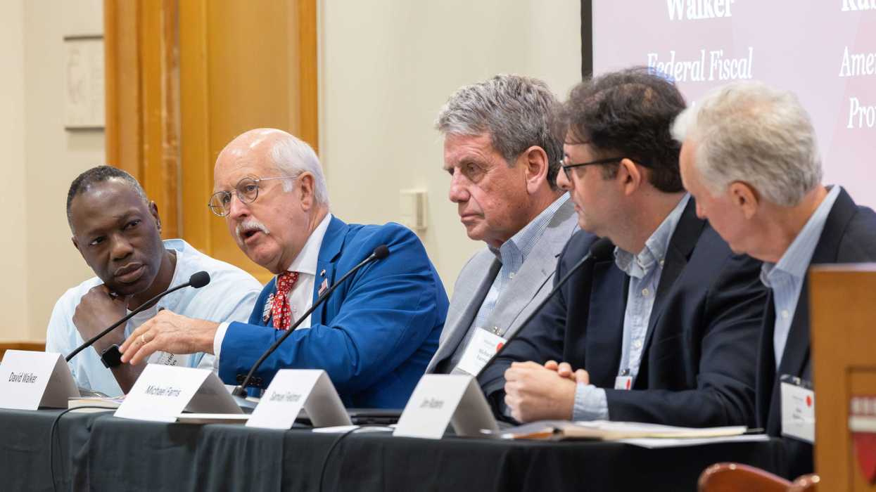 Five men sitting on one side of a table, as a panel at an event.