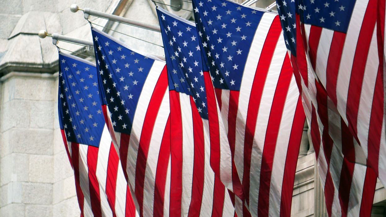 Flags of the United States hanging in front of the facade of a building