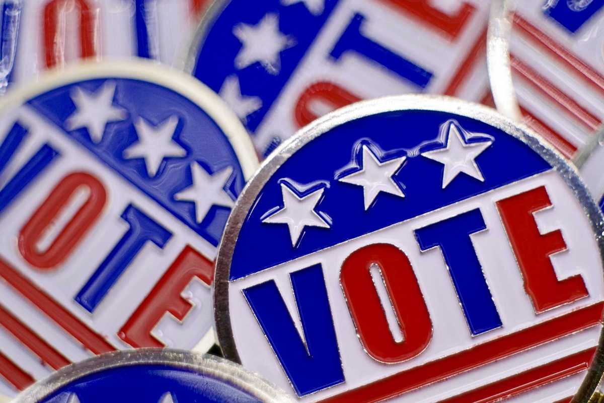 Full frame shot of pins that say “vote” with red, white, and blue American flag theme.