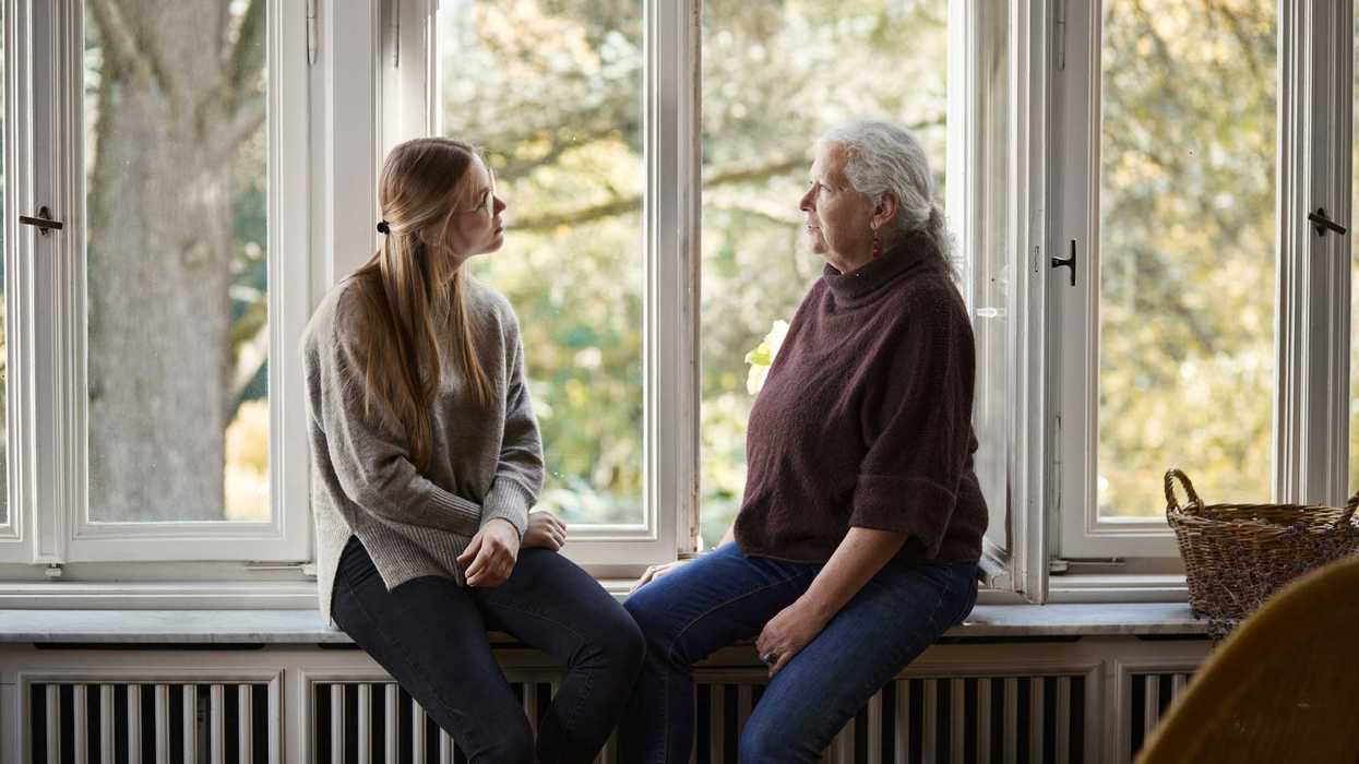 Grandmother and adult granddaughter sitting on windowsill