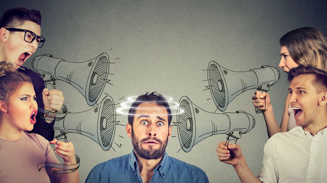 Group of people screaming in megaphones at scared guy