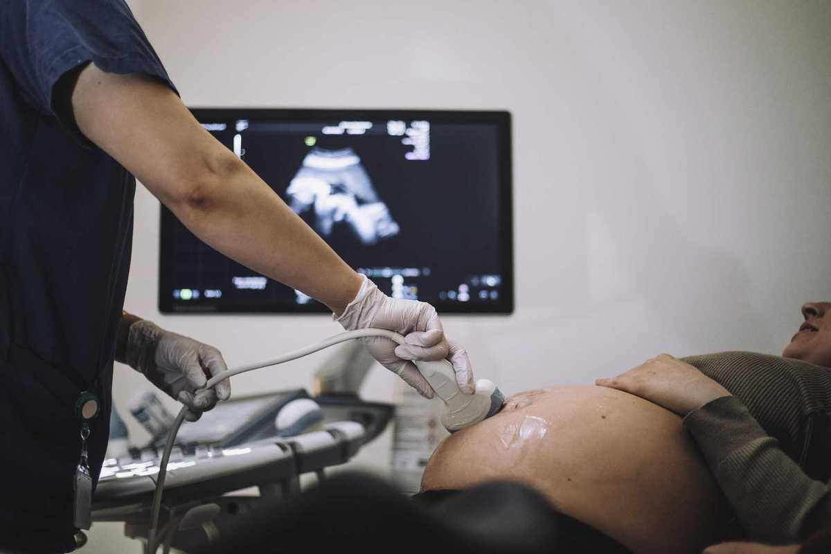 Gynecologist doing ultrasound of pregnant woman in hospital.