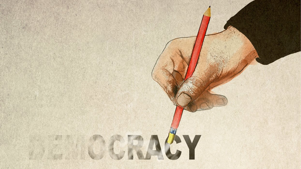 Hand erasing the word "democracy"