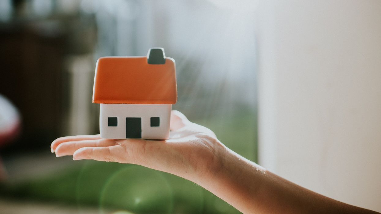 Hand holding a little house with an orange roof. Conceptual image.
