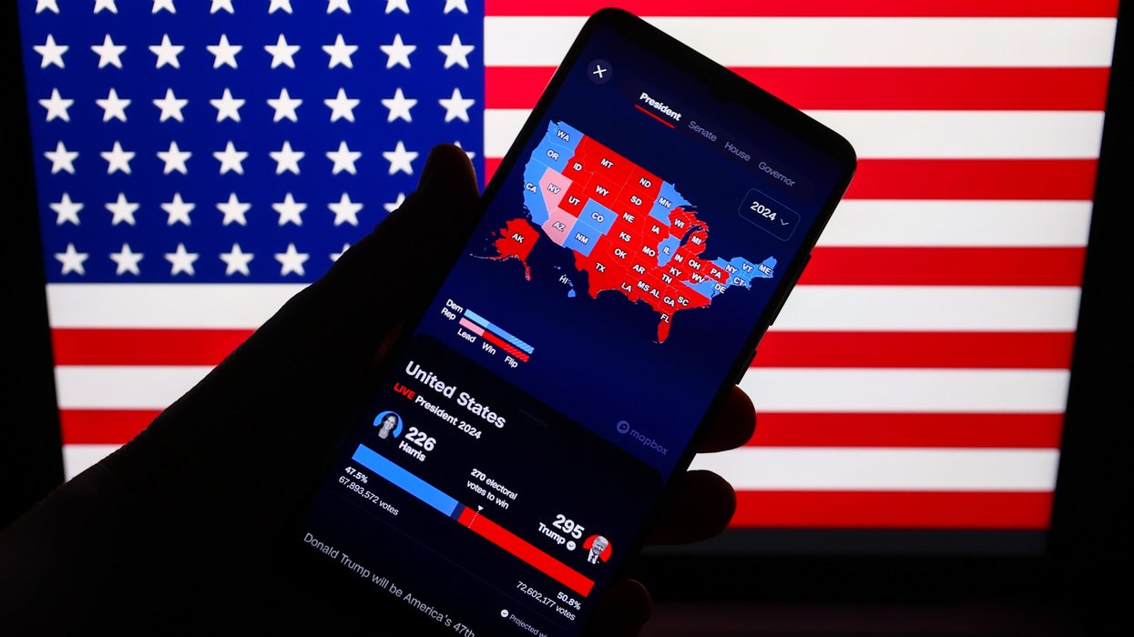 Hand holding a mobile phone showing CNN's "Magic Wall."