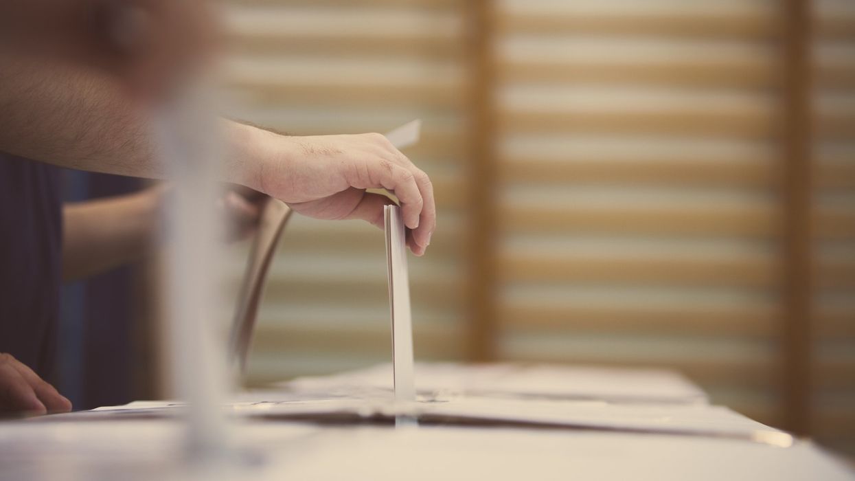 Hand of a person casting a ballot at a polling station during voting.