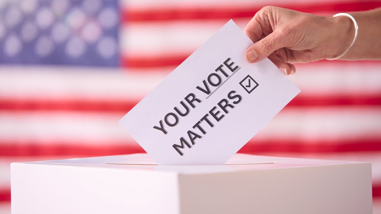 Hand Placing Ballot in Box With American Flag