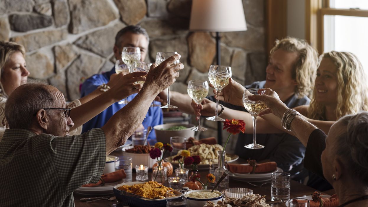 Happy family raising toast while sitting together at dining table during Thanksgiving